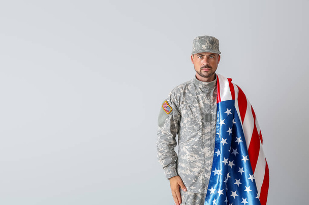 Soldado con bandera nacional de Estados Unidos sobre fondo claro
 - Foto, imagen
