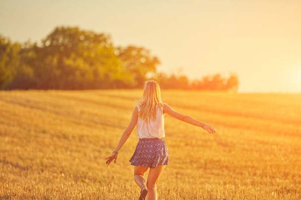 Χαριτωμένο νεαρή γυναίκα άλμα σε ένα χωράφι σιταριού. - Φωτογραφία, εικόνα