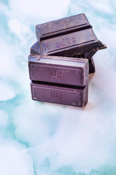 Одиниці шоколаду, складені на синьому мармурі
. - Фото, зображення