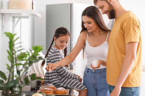 Young family with freshly baked buns in kitchen - Foto, afbeelding