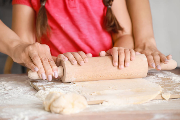 Mother with little daughter kneading dough together in kitchen - Photo, Image