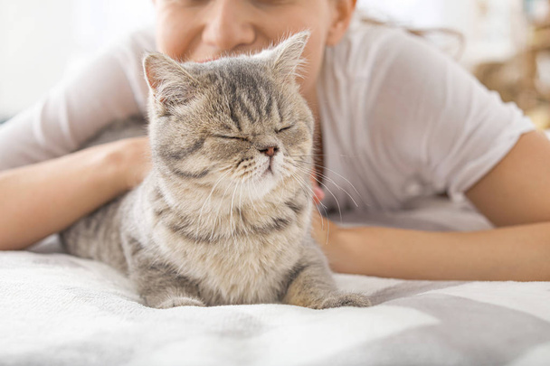 schöne junge Frau mit süßer Katze im Schlafzimmer - Foto, Bild