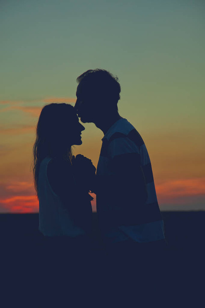 Silhouettes of a couple in sunset / sunrise time. - Foto, imagen