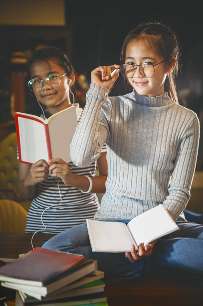 zwei asiatische Teenager und booket in der Hand sitzen in der Bibliothek  - Foto, Bild
