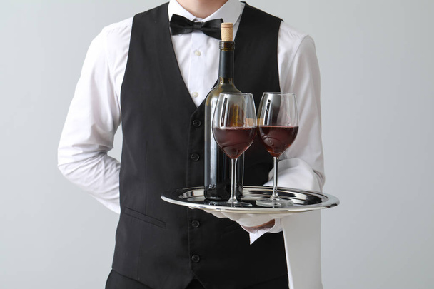 Handsome waiter with wine on light background - Photo, Image