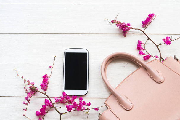 rosa colección de bolsos de mano de la mujer de moda de estilo de vida con teléfono móvil, rosa arreglo de flores pequeñas estilo de laico plano sobre fondo blanco de madera
 - Foto, imagen