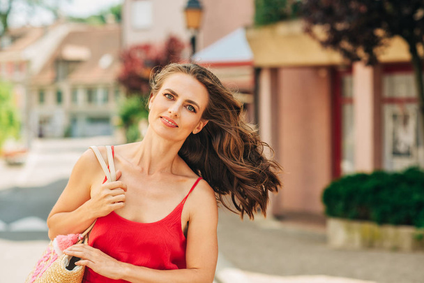 Retrato de verão de mulher feliz com belo estilo de cabelo, vestindo vestido vermelho, andando pela rua
 - Foto, Imagem