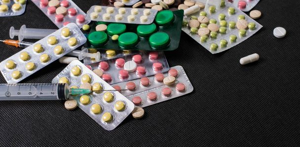 Фармацевтические антибиотики таблетки лекарства / красочные антибактериальные таблетки на черном фоне / капсулы таблетки медицины. Творческая идея. Наркотики. Печально. Умереть. Болезнь
 - Фото, изображение