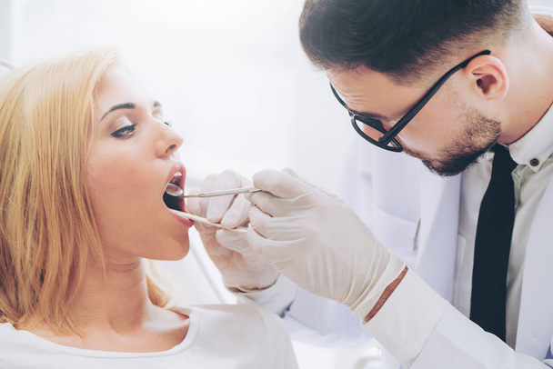 Nuori hammaslääkäri tutkii potilasta hammashoitolassa
. - Valokuva, kuva