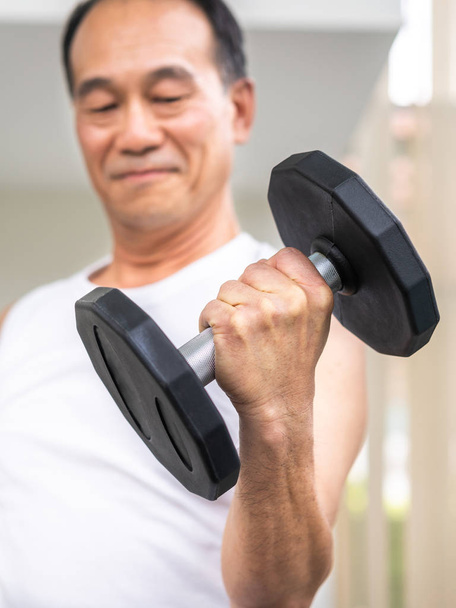 Senior man lifting dumbbell in fitness gym. - Photo, Image