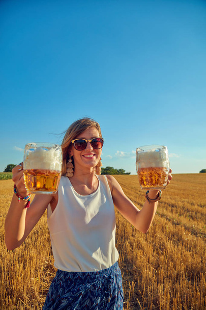 glückliches Mädchen mit Bierglas in einem großen Weizenfeld. - Foto, Bild