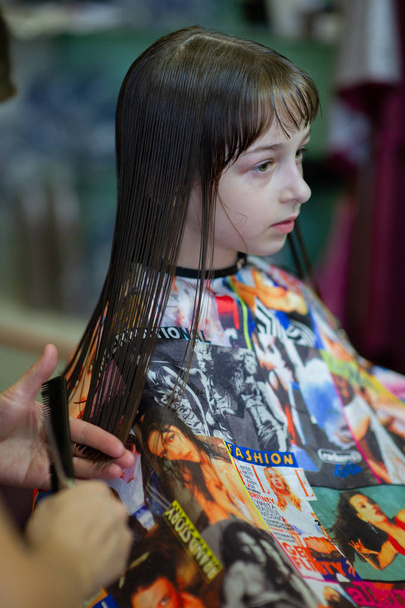 Kadeřník stylistka dělá účes pro roztomilou holčičku v kadeřnictví krásy. Kadeřnictví, stříhání vlasů. - Fotografie, Obrázek