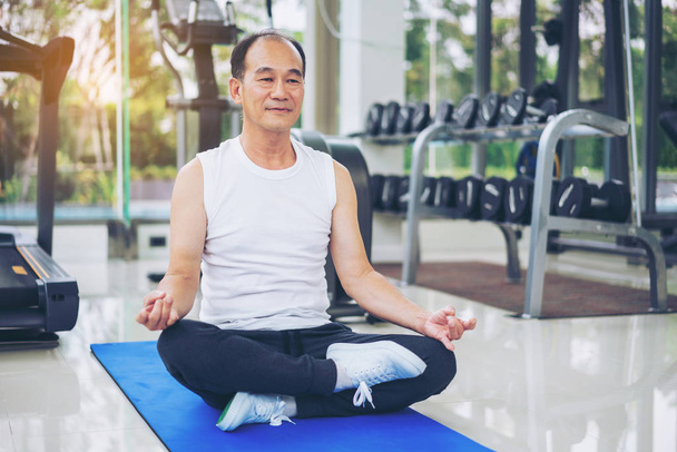 Senior man practice yoga in fitness gym. - Фото, зображення