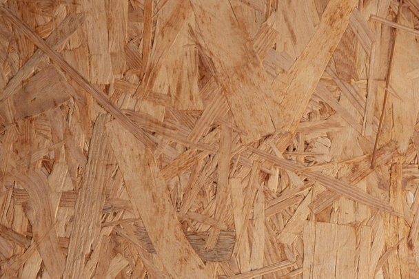 Natural background from pressed wood sawdust. Large particles of wood are visible in the structure. - Foto, afbeelding
