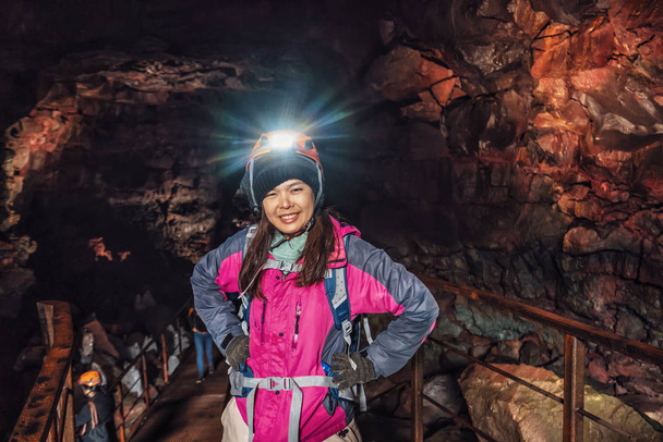 Mujer viajera explora túnel de lava en Islandia
. - Foto, Imagen