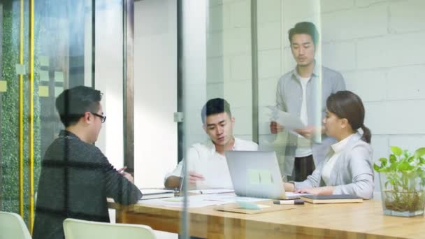Skupina mladých asijských podnikatelů diskutuje o podnikání v firemní zasedající místnosti - Záběry, video