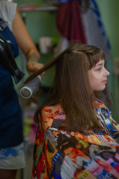 Peluquería estilista hace un peinado para una niña linda en un salón de belleza. Peluquería, corte de pelo
. - Foto, Imagen