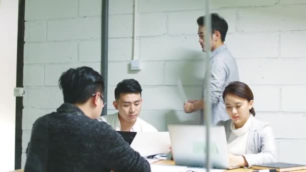 ομάδα νεαρών ασιατικών επιχειρηματιών που συζητούν για τις επιχειρήσεις στην αίθουσα συσκέψεων της εταιρείας - Πλάνα, βίντεο