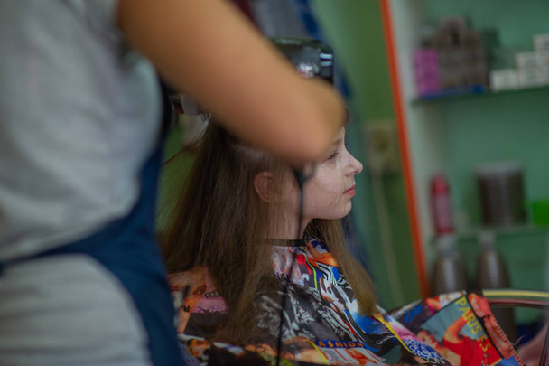 Peluquería estilista hace un peinado para una niña linda en un salón de belleza. Peluquería, corte de pelo
. - Foto, Imagen