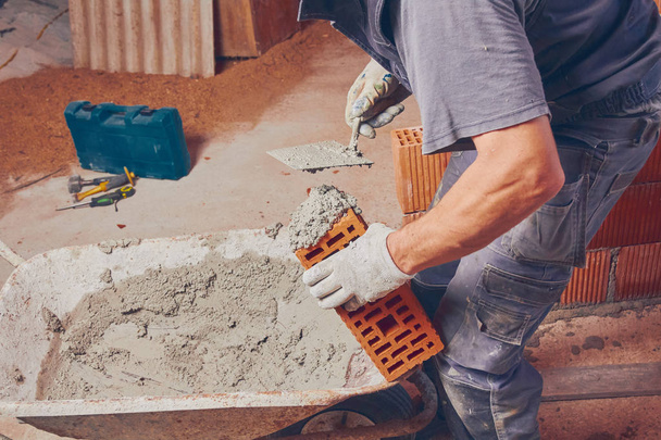 Trabalhador da construção real tijolo que coloca a parede dentro de casa
. - Foto, Imagem