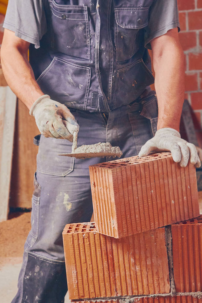 Real construction worker bricklaying the wall indoors. - Photo, Image