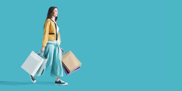 Smiling woman walking and holding shopping bags - Foto, Bild
