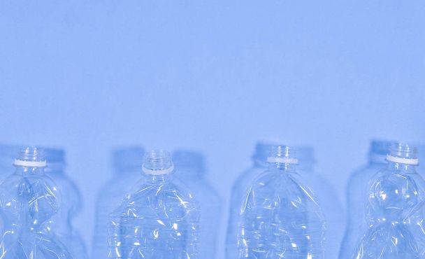 Пластиковые бутылки изолированы на синем фоне. Бесшовный шаблон. Концепция утилизации отходов. Пластиковые бутылки для домашних животных. Копирование пространства
 - Фото, изображение