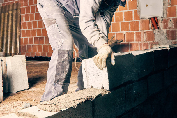 Πραγματική κατασκευή εργαζόμενος κτίσιμο τοίχου σε εσωτερικούς χώρους. - Φωτογραφία, εικόνα