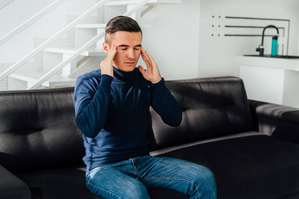 Man sitting on the couch feeling a headache - Photo, image