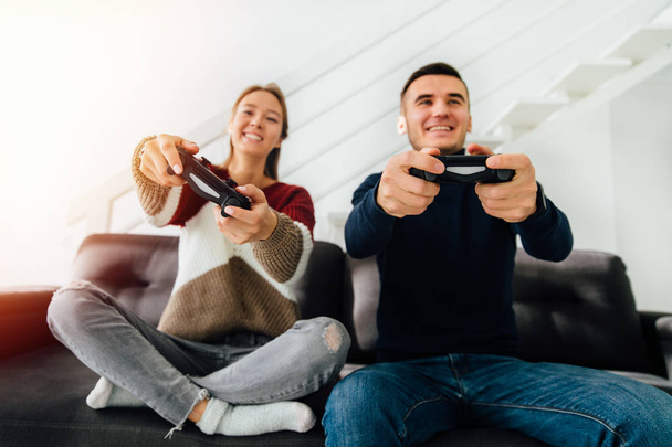 Smiling girl and guy playing video games using joysticks - Valokuva, kuva
