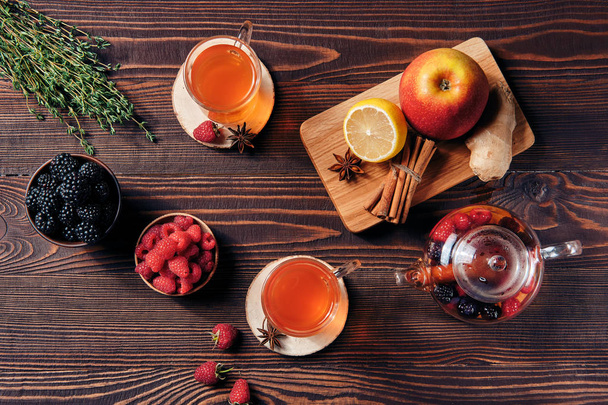 Tè alla frutta con lamponi, rovo, mela e limone in tazze e teiera
 - Foto, immagini
