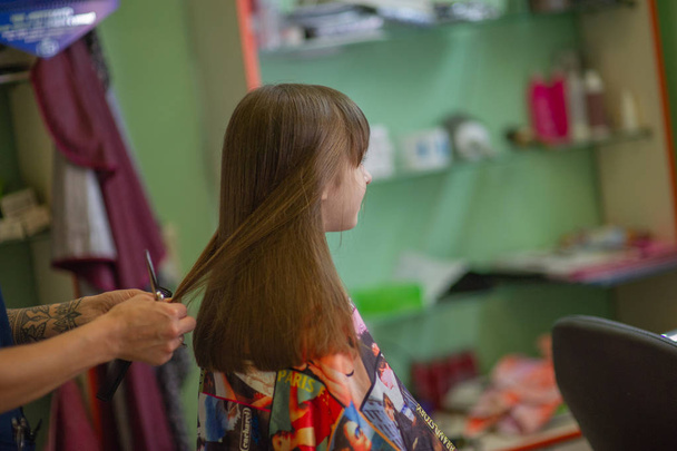 Stylist fodrász teszi a frizurát egy aranyos kislány egy szépségszalonban. Fodrászati, hajvágás. - Fotó, kép