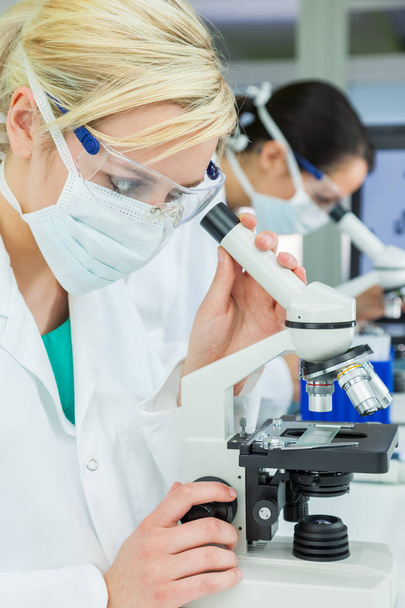 Female Scientific Research Team Scientists Using Microscopes in  - Photo, Image