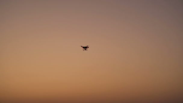 Silhouette of drone with digital camera flying on sunset. - Záběry, video