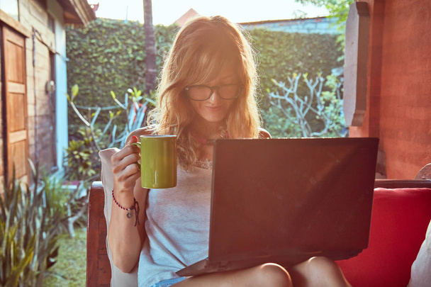 Freelancer girl working on a vacation / at home patio porch. - Photo, Image