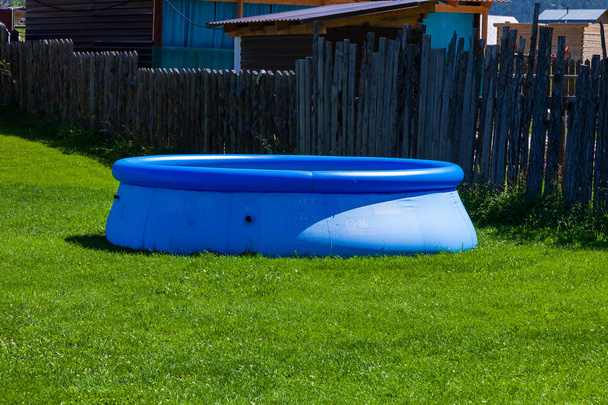 Синий надувной резиновый бассейн на лужайке зеленой травы в котловане
 - Фото, изображение