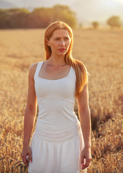 Joven mujer deportiva en vestido blanco, pelo largo y castaño, mirando en
 - Foto, Imagen
