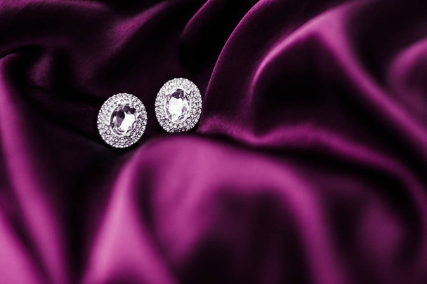 Orecchini di diamanti di lusso su tessuto di seta rosa scuro, glamou vacanza
 - Foto, immagini