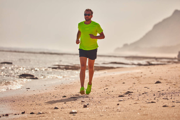 Férfi futás/kocogás egy trópusi egzotikus strandon. - Fotó, kép