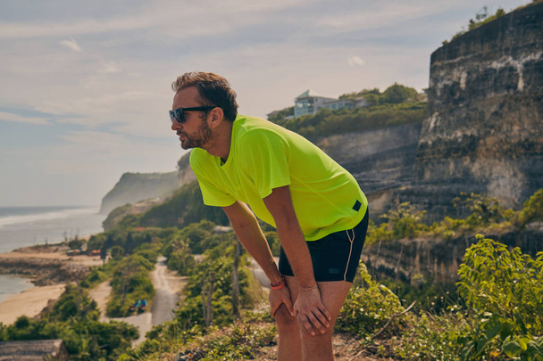 Sportsman stretching on a tropical exotic cliff near the ocean. - Fotografie, Obrázek
