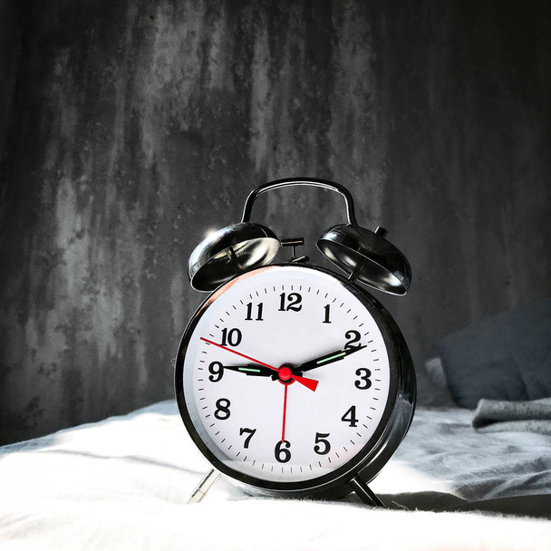 Reloj despertador metálico con luz solar en la cama
 - Foto, Imagen
