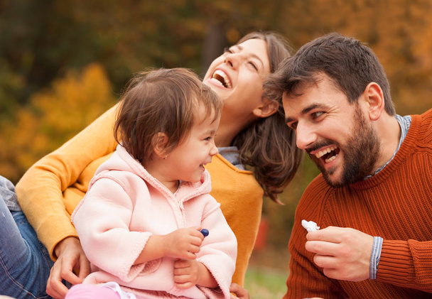 Щаслива сім'я сміється і розважається разом на пікніку в осінньому парку
. - Фото, зображення