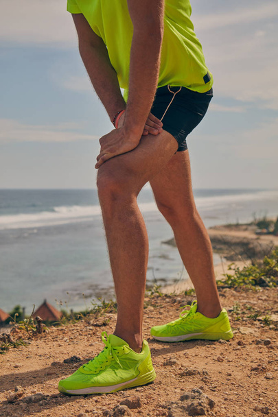 Sportsman stretching on a tropical exotic cliff near the ocean. - Φωτογραφία, εικόνα