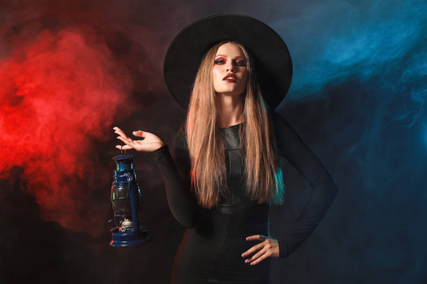 Mooie vrouw verkleed als heks voor Halloween op donkere achtergrond - Foto, afbeelding