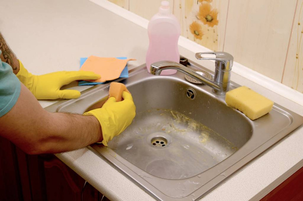 Persona o capofamiglia che pulisce il lavello con spugna in primo piano
 - Foto, immagini