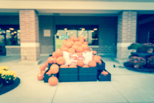 Filtered image blurry background Halloween pumpkins and flowers at supermarket entrance - Photo, Image