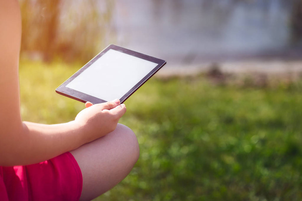 Menina está lendo ebook no banco perto do mar
 - Foto, Imagem