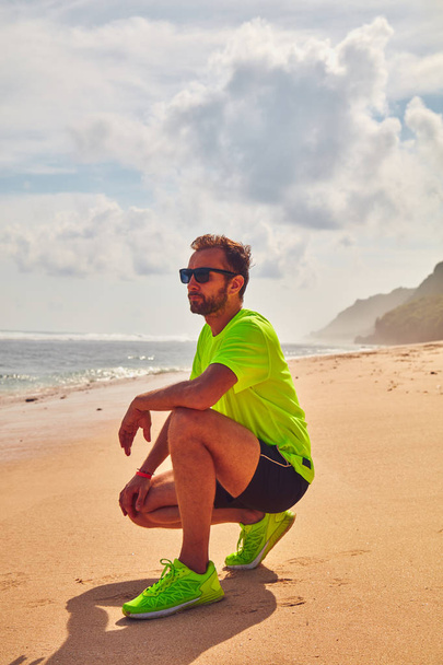 Sportman op een tropische exotische klif in de buurt van de Oceaan. - Foto, afbeelding