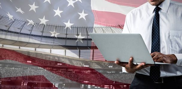 Sección media del hombre de negocios usando un portátil contra el primer plano de una bandera americana
 - Foto, Imagen