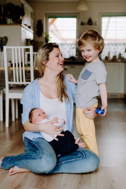 A beautiful young mother with a newborn baby and his brother at home. - Valokuva, kuva